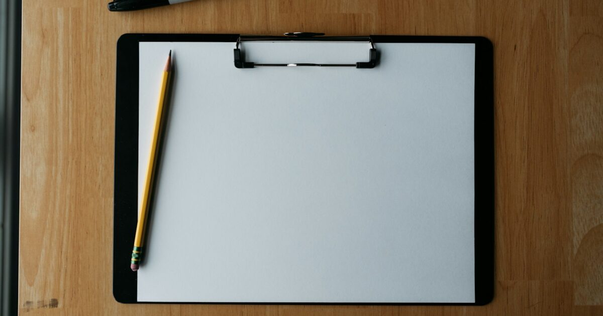 Blank painting estimate clipboard with yellow pencil on wooden desk