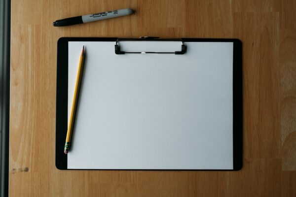 Blank painting estimate clipboard with yellow pencil on wooden desk